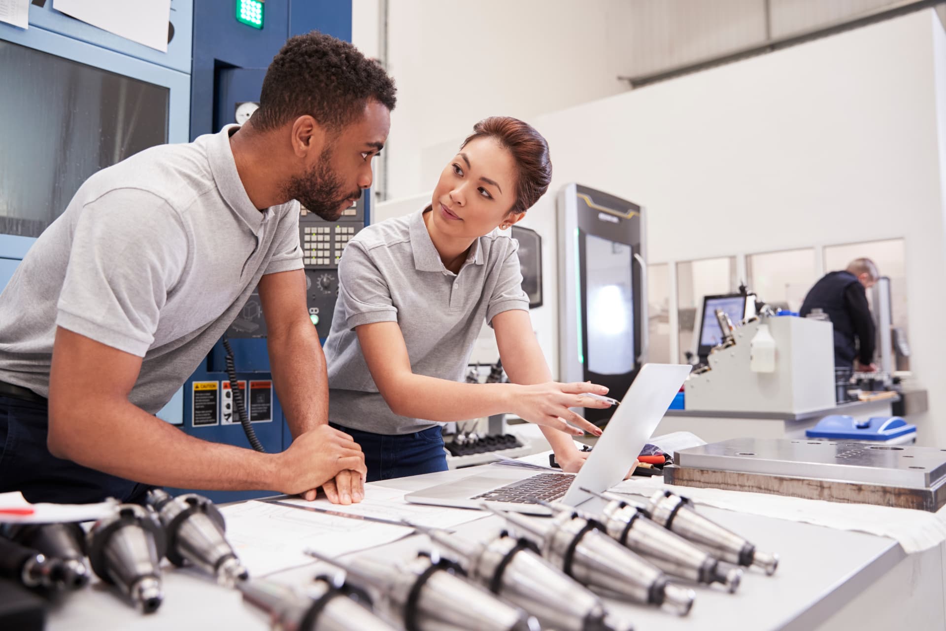 Two engineers reviewing plans at a laptop on a modern plant floor